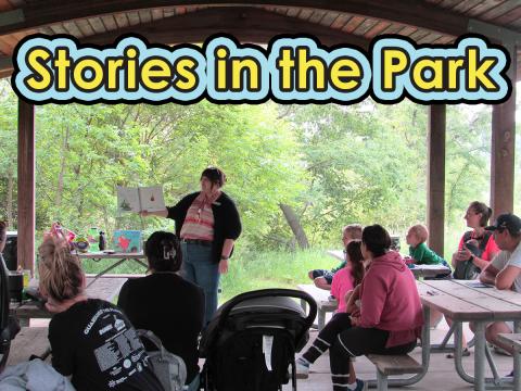 Librarian reading a picture book outside to group of families