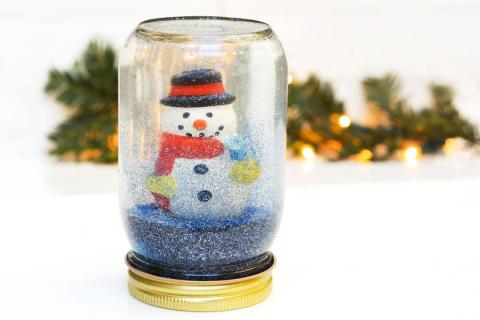 Snowman inside a snow globe that's made out of an upside-down jar