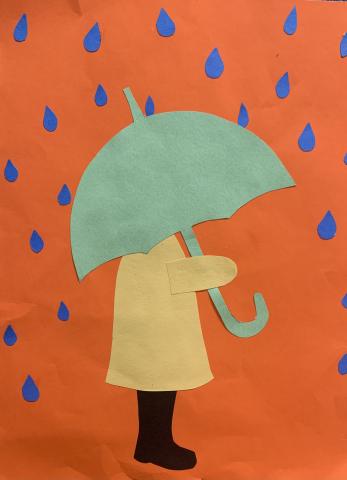 child in yellow jacket with green umbrella against orange paper background