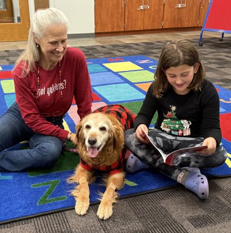 Woman, dog, and child reading a book
