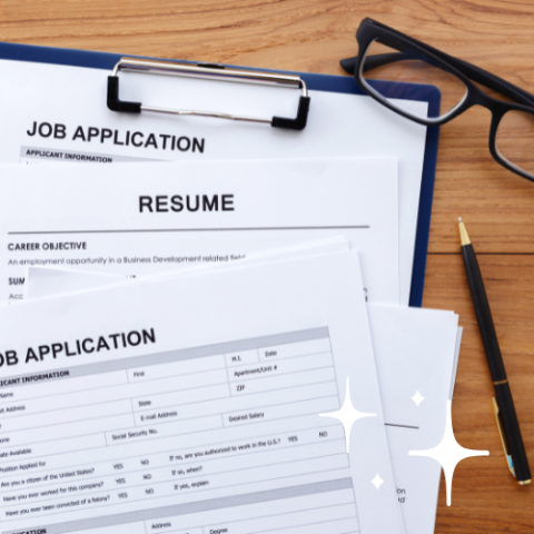 Resumes and job applications on a clipboard, with reading glasses and a black pen on a waiting table