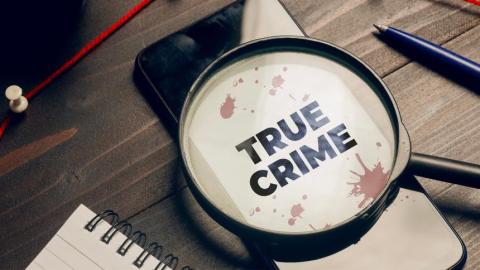 Magnifying glass with the phrase True Crime on a notebook