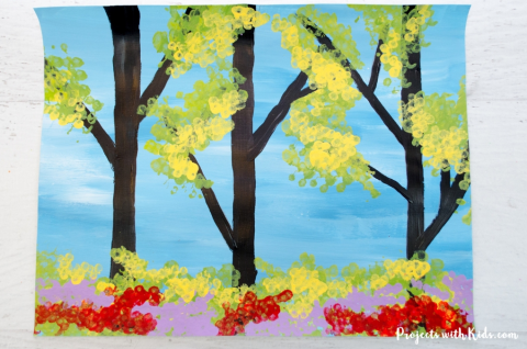 Artwork with blue background yellow, purple, and red dots, and black trees