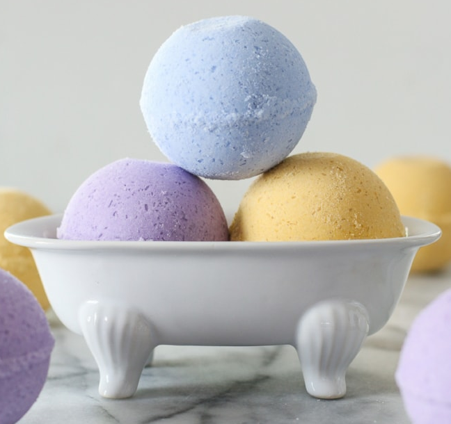 Purple, blue, and yellow bath bombs in white tub